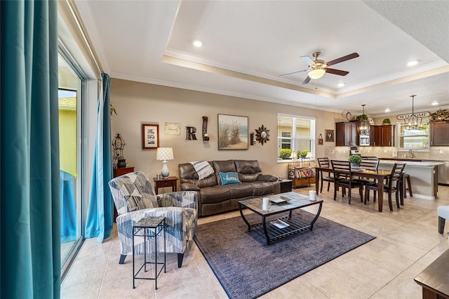 living room featuring a raised ceiling, ceiling fan, crown molding, and light tile patterned flooring