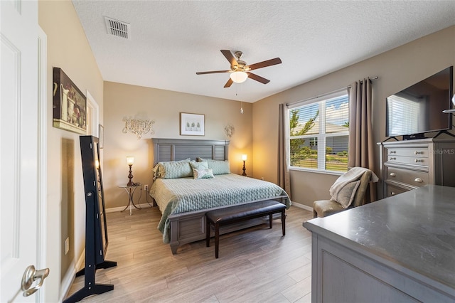 bedroom featuring ceiling fan, a textured ceiling, and light hardwood / wood-style flooring