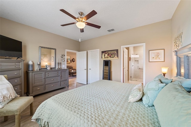 bedroom with a textured ceiling, ceiling fan, light hardwood / wood-style flooring, and ensuite bath