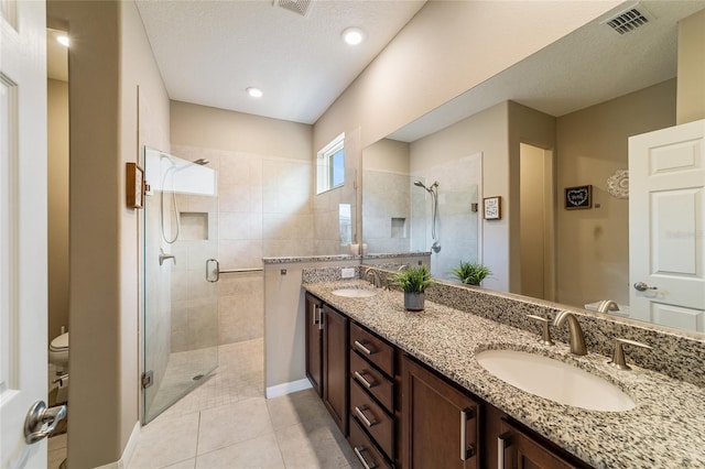 bathroom featuring toilet, vanity, tile patterned floors, and an enclosed shower