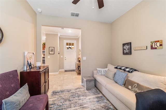 living room with ceiling fan, crown molding, light tile patterned floors, and a textured ceiling