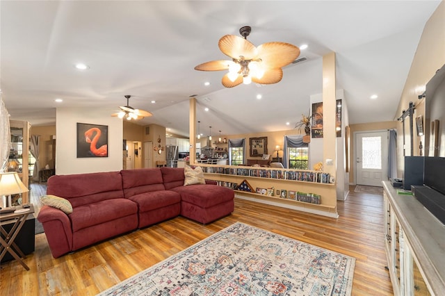 living room with vaulted ceiling, ceiling fan, light hardwood / wood-style flooring, and a barn door