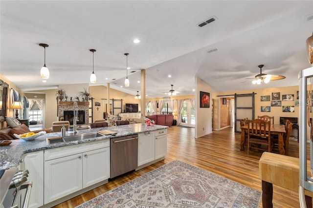 kitchen featuring stainless steel appliances, ceiling fan, stone counters, and a barn door