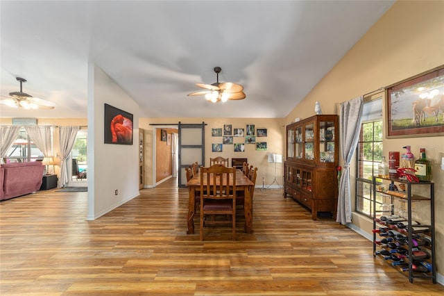 dining space featuring ceiling fan, light hardwood / wood-style floors, a barn door, and a healthy amount of sunlight