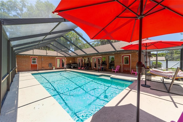 view of swimming pool featuring a patio and glass enclosure