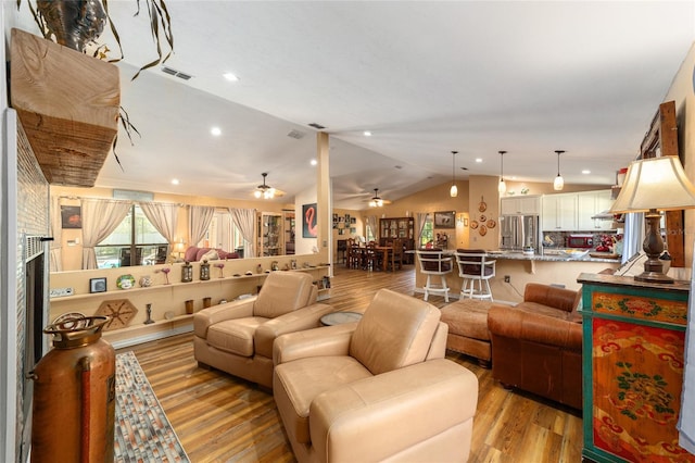 living room featuring ceiling fan, light wood-type flooring, and vaulted ceiling