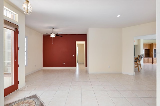 spare room with ceiling fan with notable chandelier and light tile patterned flooring