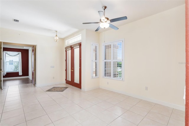 tiled entrance foyer featuring plenty of natural light and ceiling fan with notable chandelier