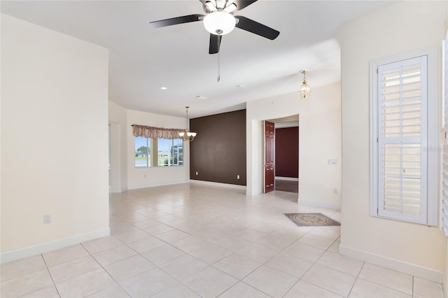 empty room with ceiling fan with notable chandelier and light tile patterned floors