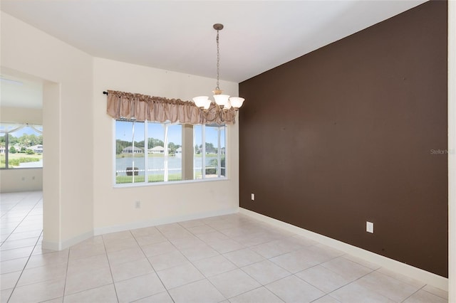 empty room with light tile patterned flooring, a water view, and a chandelier