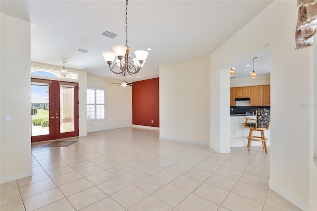 empty room with french doors, ceiling fan with notable chandelier, and light tile patterned floors