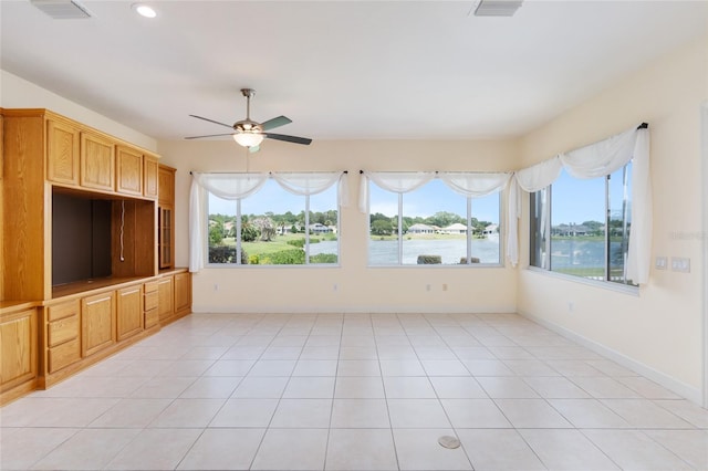 unfurnished sunroom featuring ceiling fan, a water view, and a healthy amount of sunlight