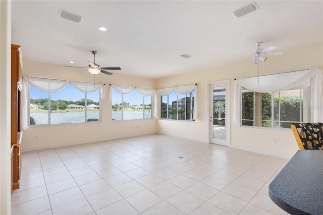 unfurnished sunroom featuring ceiling fan and a water view