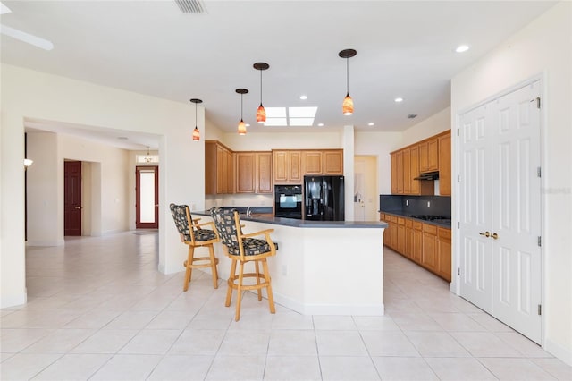 kitchen featuring black appliances, a breakfast bar, light tile patterned floors, and kitchen peninsula