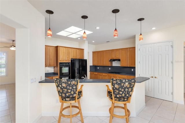 kitchen featuring black appliances, a breakfast bar, pendant lighting, and a skylight