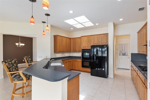 kitchen featuring kitchen peninsula, a skylight, black appliances, decorative light fixtures, and a chandelier