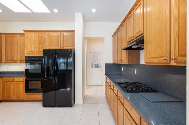 kitchen with tasteful backsplash, a skylight, light tile patterned floors, and black appliances