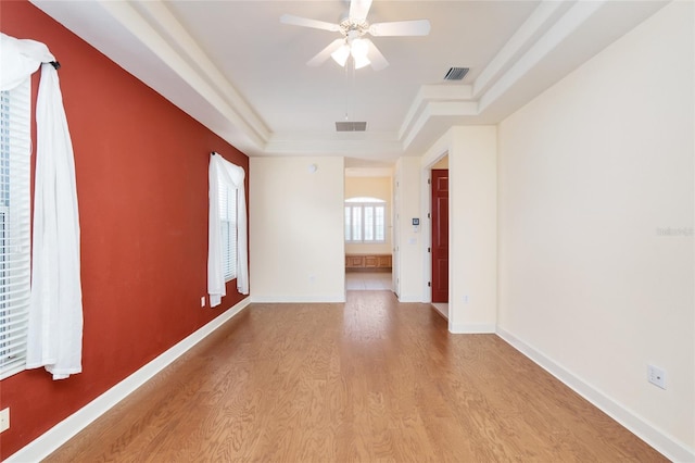 spare room with ceiling fan, light hardwood / wood-style floors, and a raised ceiling