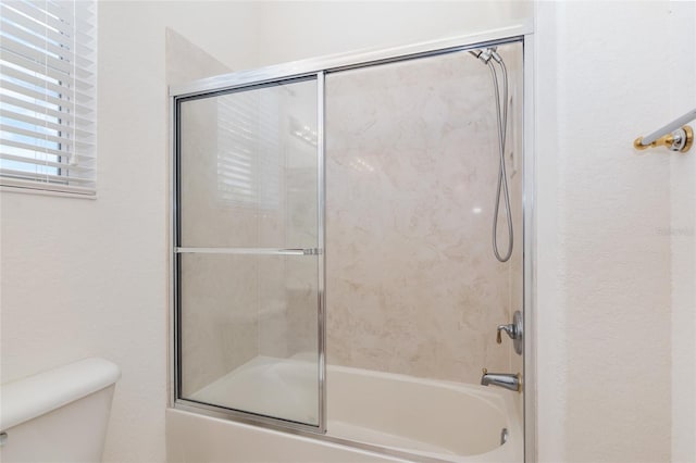 bathroom featuring shower / bath combination with glass door and toilet