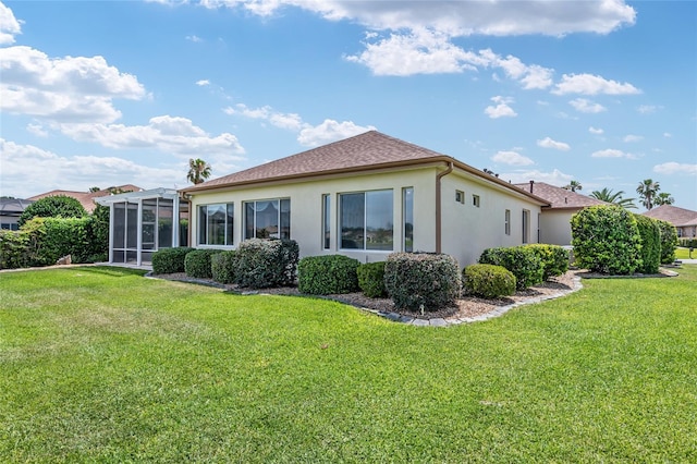 back of property featuring a lawn and glass enclosure