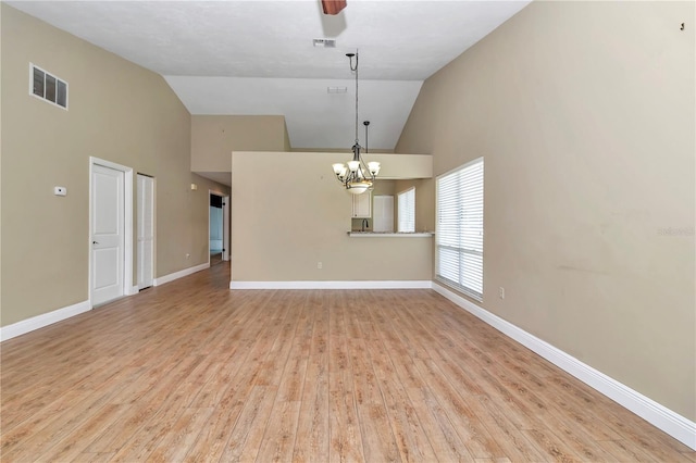 unfurnished room featuring ceiling fan with notable chandelier, high vaulted ceiling, and light hardwood / wood-style flooring