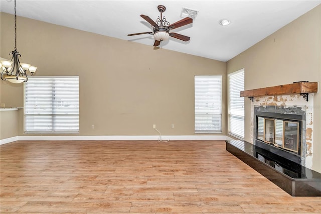 unfurnished living room with ceiling fan with notable chandelier, light wood-type flooring, and lofted ceiling