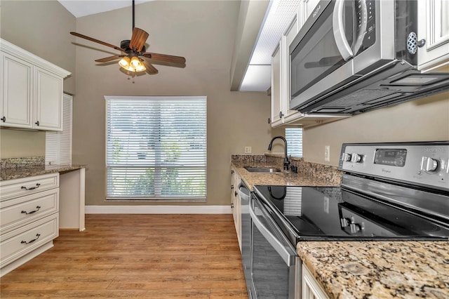 kitchen featuring lofted ceiling, white cabinets, sink, light wood-type flooring, and stainless steel appliances