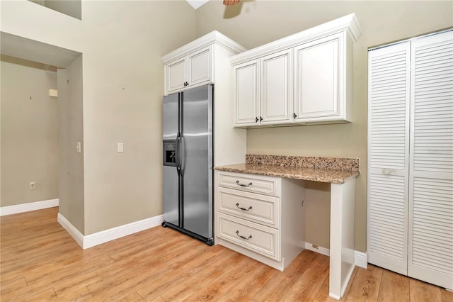 kitchen featuring white cabinets, light hardwood / wood-style floors, built in desk, and stainless steel fridge with ice dispenser