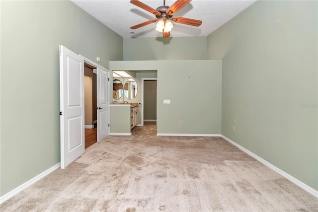 unfurnished room with ceiling fan, light carpet, and a high ceiling