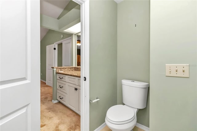 bathroom featuring vanity, toilet, and lofted ceiling