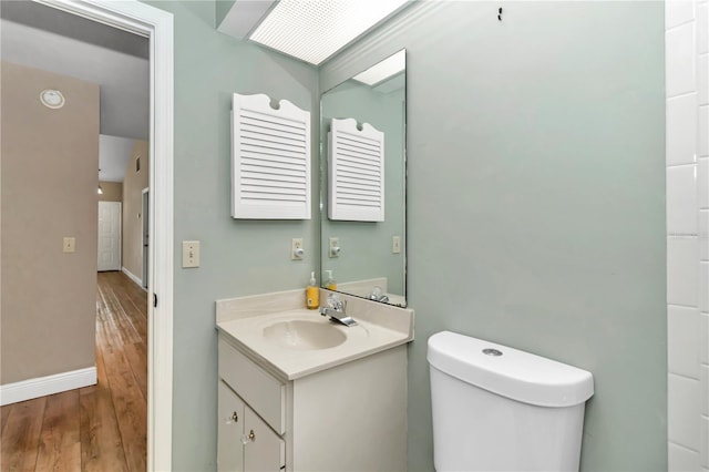 bathroom with hardwood / wood-style floors, vanity, and toilet