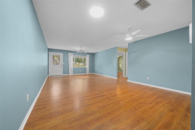 empty room featuring baseboards, visible vents, ceiling fan, and wood finished floors