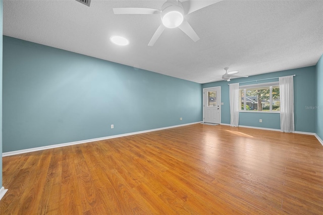 unfurnished room featuring a textured ceiling, wood finished floors, a ceiling fan, and baseboards