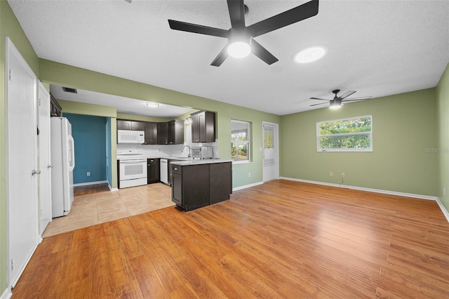 kitchen with light countertops, open floor plan, a sink, light wood-type flooring, and white appliances