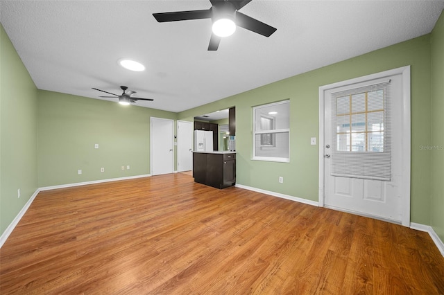 unfurnished living room with a ceiling fan, light wood-style flooring, and baseboards