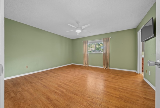 unfurnished room featuring a ceiling fan, light wood-style flooring, baseboards, and a textured ceiling