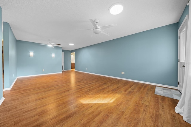 unfurnished room featuring ceiling fan, a textured ceiling, baseboards, and wood finished floors