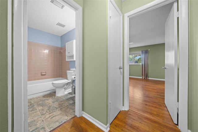 bathroom featuring visible vents, wood finished floors, toilet, and baseboards