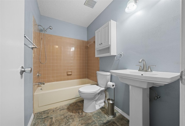 bathroom with baseboards, visible vents, toilet, a textured ceiling, and shower / washtub combination