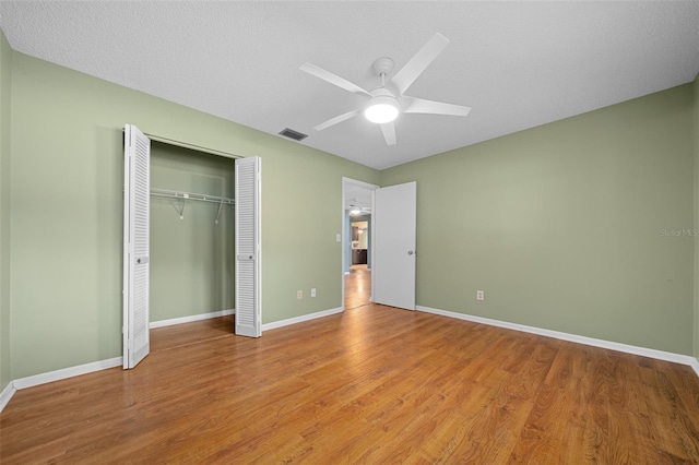 unfurnished bedroom featuring visible vents, a closet, baseboards, and wood finished floors