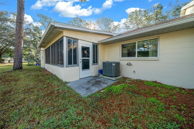 exterior space with cooling unit, a sunroom, and a lawn