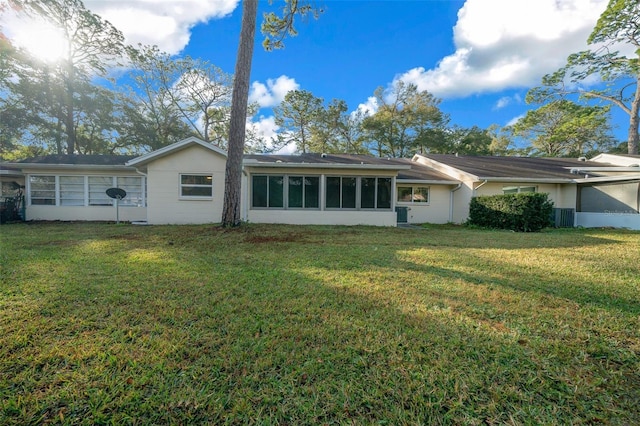 rear view of house with a sunroom, a yard, and central AC unit