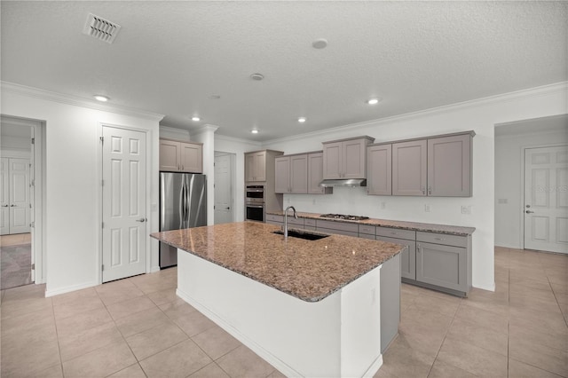 kitchen with a textured ceiling, sink, stainless steel appliances, and a kitchen island with sink