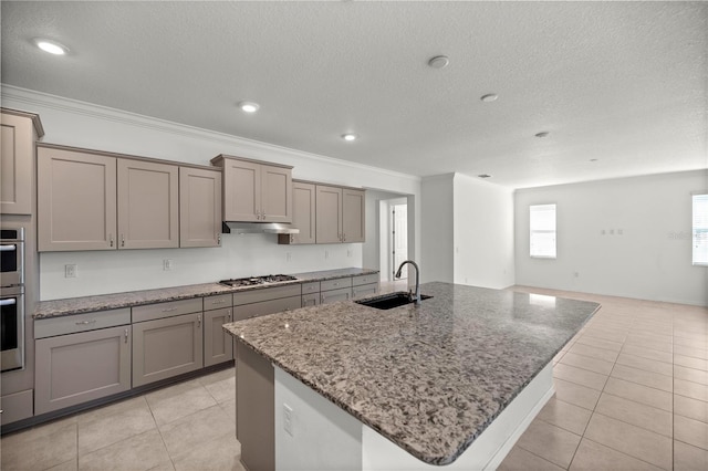 kitchen featuring a kitchen island with sink, sink, ornamental molding, and stainless steel gas stovetop