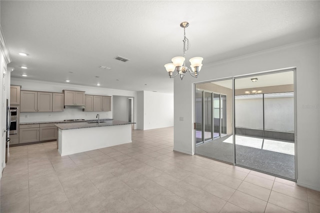 kitchen with pendant lighting, crown molding, sink, an island with sink, and a notable chandelier