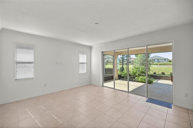 empty room featuring crown molding, light tile patterned flooring, and a textured ceiling