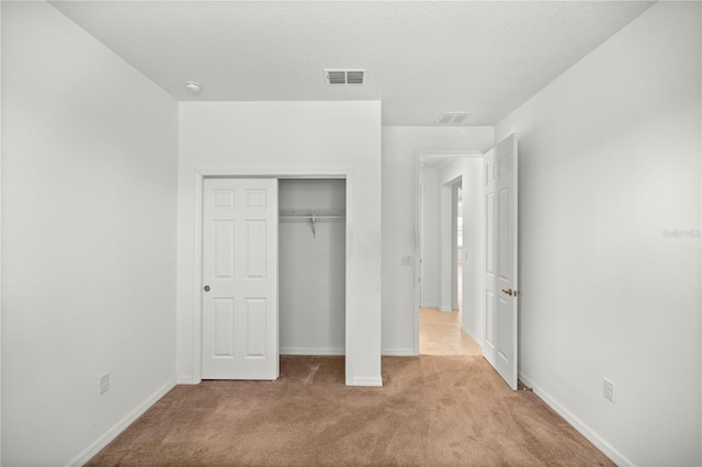 unfurnished bedroom featuring light carpet and a closet