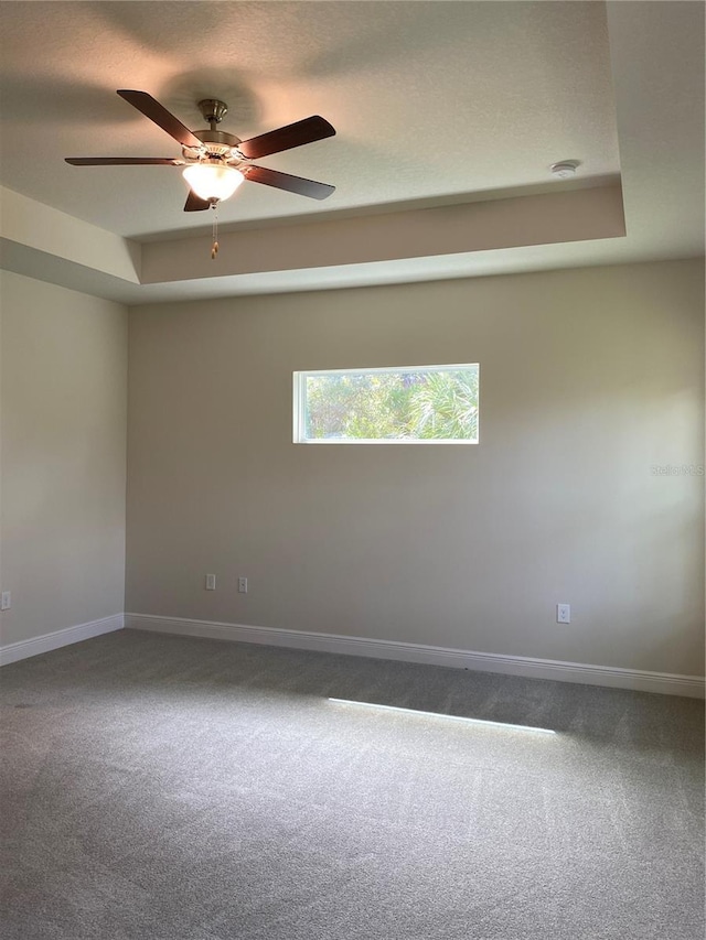 unfurnished room with carpet flooring, a raised ceiling, ceiling fan, and a textured ceiling