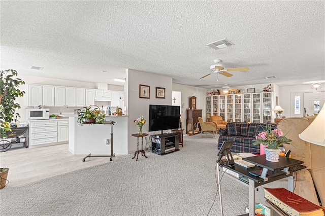 living room featuring ceiling fan, light carpet, and a textured ceiling