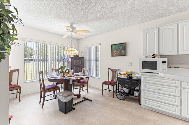 dining room featuring ceiling fan and a textured ceiling